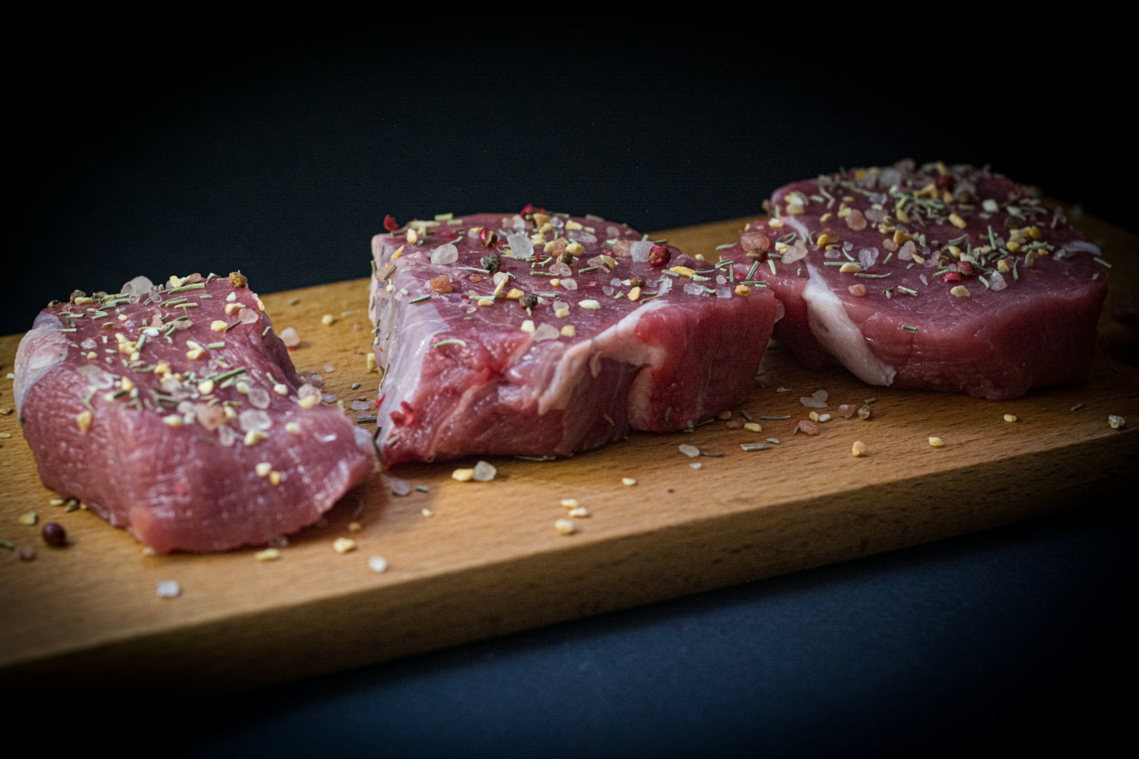 two pieces of raw meat sit on a cutting board